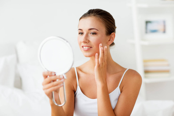 beautiful woman with mirror touching her face skin - Fotó, kép
