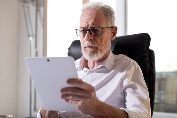 Senior businessman using a digital tablet, hard light - Foto, afbeelding