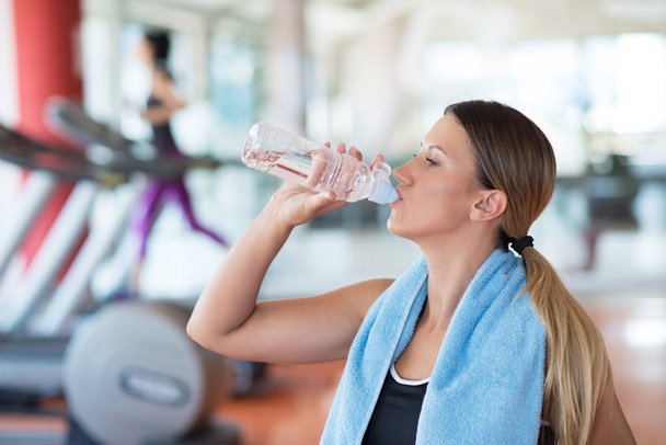 girl in gym drinking water - Foto, imagen