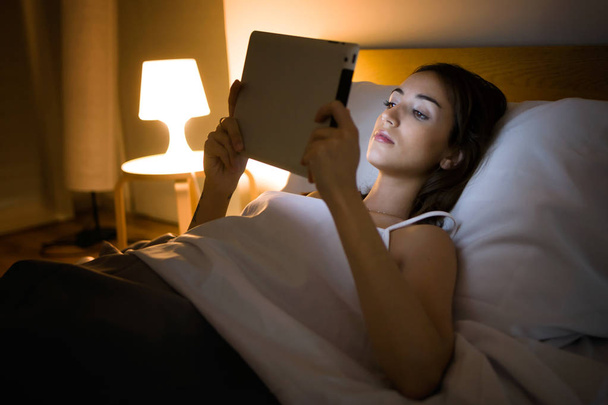 Gyönyörű fiatal nő segítségével a digitális tábla, az ágyban, a kékes-Szabóné Edit - Fotó, kép