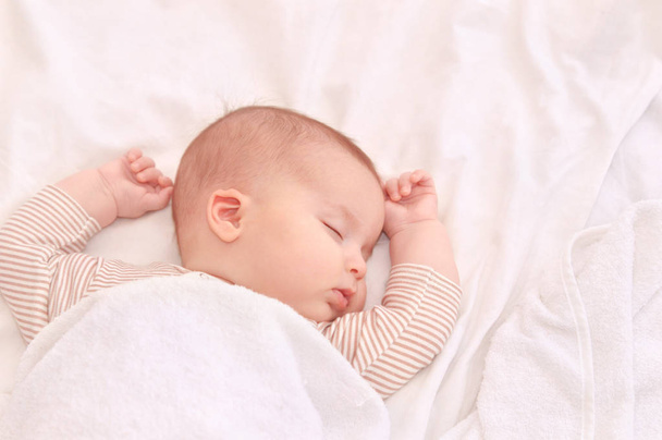 Peaceful baby lying on a bed while sleeping in a bright room - Photo, image