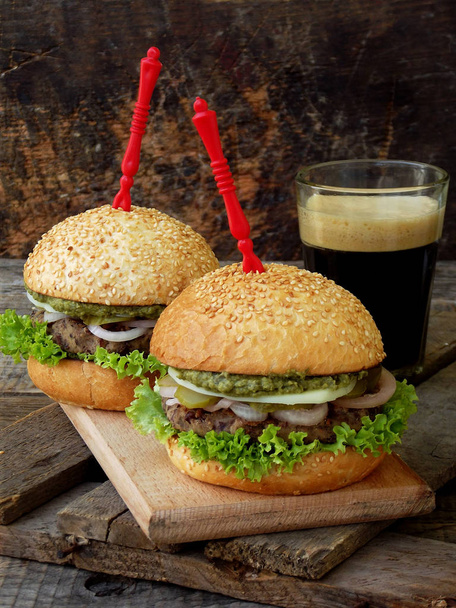 Veggie hamburgers met een hak van zwarte bonen, sla, uien ingemaakte komkommer op een bruin houten achtergrond. - Foto, afbeelding