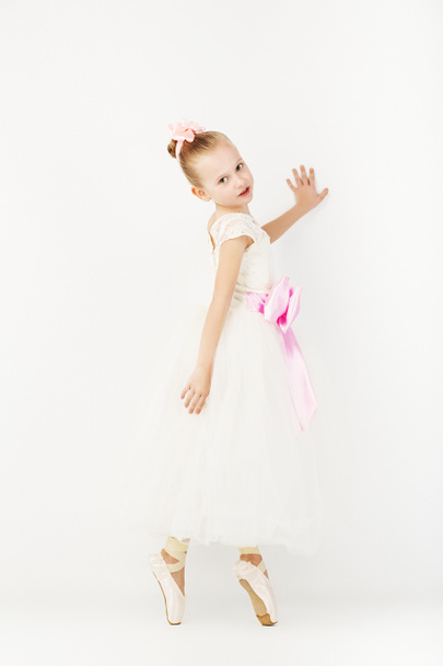 Прекрасный балетный танцор на белом фоне. Стройная маленькая балерина в белом платье и в пуантах
 - Фото, изображение