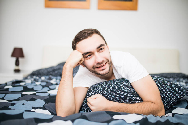 Красивий чоловік сміється лежачи на ліжку
 - Фото, зображення