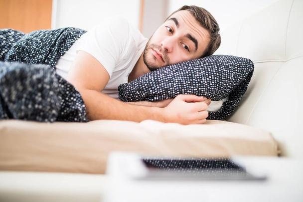 Hombre en la cama despertado por la alarma en el teléfono móvil en casa
 - Foto, imagen