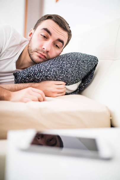 Man in bed woken by alarm on mobile phone at home - Fotó, kép