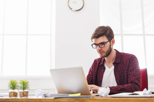 Молодой бизнесмен работает с ноутбуком в современном белом офисе
 - Фото, изображение