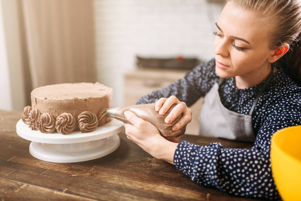 Frau dekoriert Schokoladenkuchen  - Foto, Bild