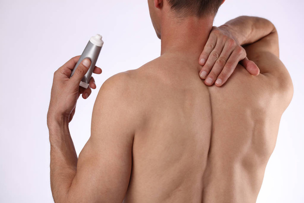 Man applying pain relieving cream, gel. Sport injury, Man with back, neck pain. Pain relief and health care concept. - Foto, imagen