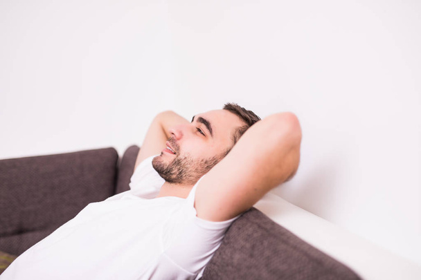 Handsome man is looking away while sitting on couch at home - Photo, image