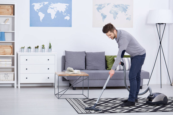 Man vacuuming in a living room - Fotoğraf, Görsel