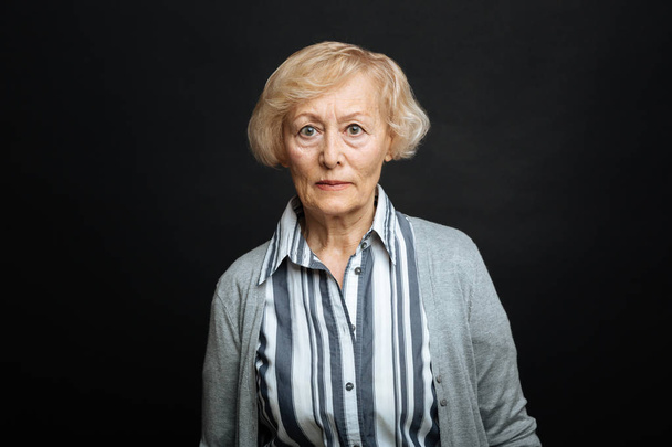 Resolute retired woman expressing anger in the black colored studio - Fotografie, Obrázek