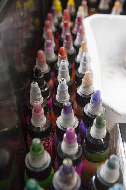 Botellas de tintas de tatuaje de colores, en una caja de salón de tatuajes
 - Foto, imagen