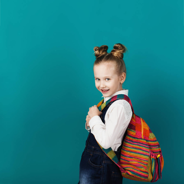Όμορφο μικρό γελαστό κοριτσάκι με μεγάλο σακίδιο στέκεται ενάντια στην - Φωτογραφία, εικόνα
