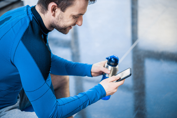 man using smartphone at gym - Foto, afbeelding
