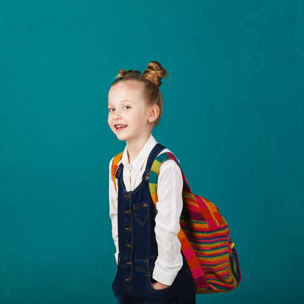 Funny smiling little girl with big backpack jumping and having f - Zdjęcie, obraz