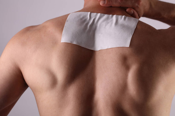 Medicated pain relief patch, plaster. man with back pain. Pain relief and health care concept. - Fotografie, Obrázek