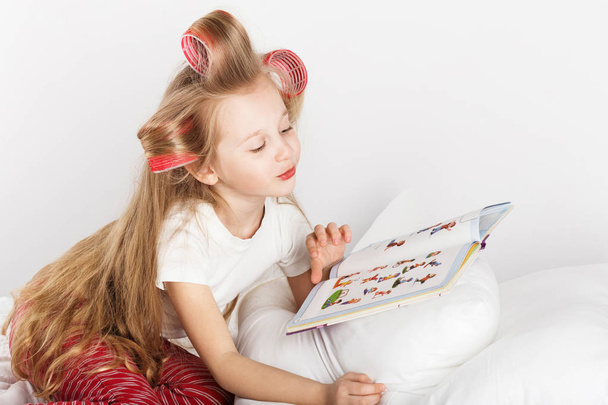 schöne Mode kleines Mädchen mit Lockenwicklern auf dem Kopf lesen ein - Foto, Bild