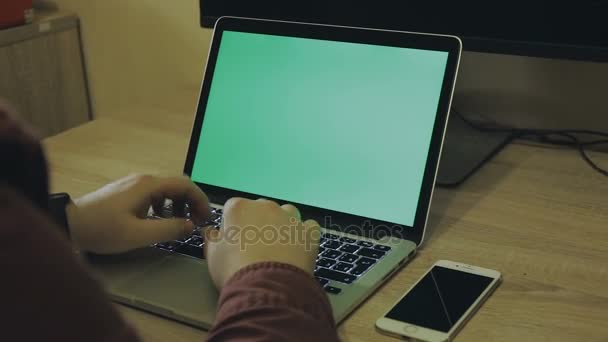 man working on a laptop, green background on the screen - Footage, Video