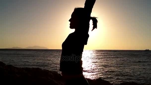 Tyttö lämpenee auringonlaskussa rannalla
. - Materiaali, video