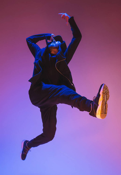 The silhouette of one hip hop male break dancer dancing on colorful background - Foto, afbeelding