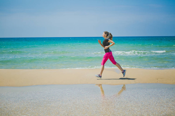 Біжить жінка. Жінка біжить під час тренування на відкритому повітрі на пляжі. Красива змішана гонка Фітнес-модель на відкритому повітрі
. - Фото, зображення