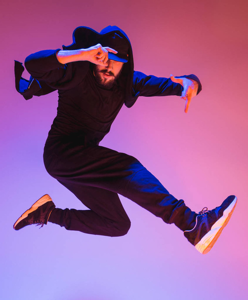 The silhouette of one hip hop male break dancer dancing on colorful background - Photo, Image