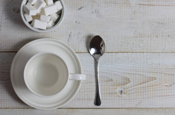 Empty tea, coffee cup with spoon and sugar on rustic wooden table. Minimalistic flat lay background - Foto, Imagem