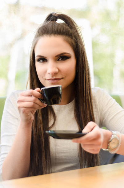 Девушка в кафе пьет кофе
 - Фото, изображение