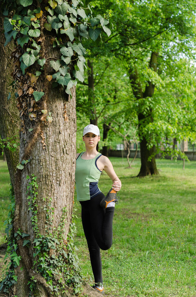 Girl with a cap exercise in the park  - Foto, Imagen