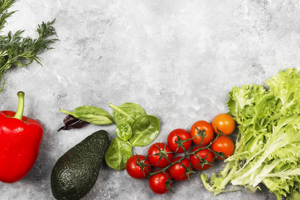 Assortment of fresh vegetables (pepper, cherry tomatoes, avocado, spinach, parsley) on a light background. Top view, copy space. Food background - Valokuva, kuva
