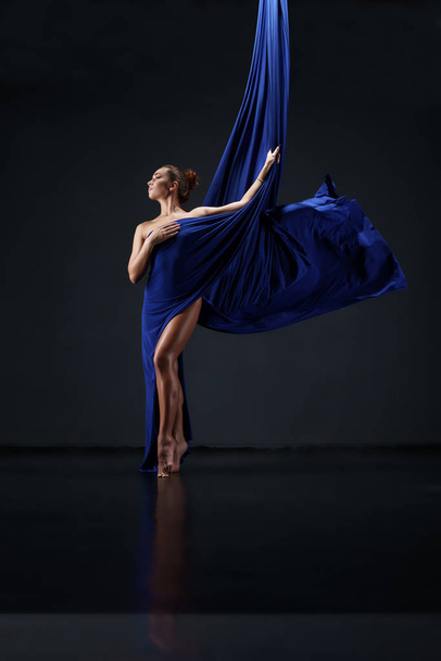 Slim girl wrapped in blue aerial silks - Foto, Bild