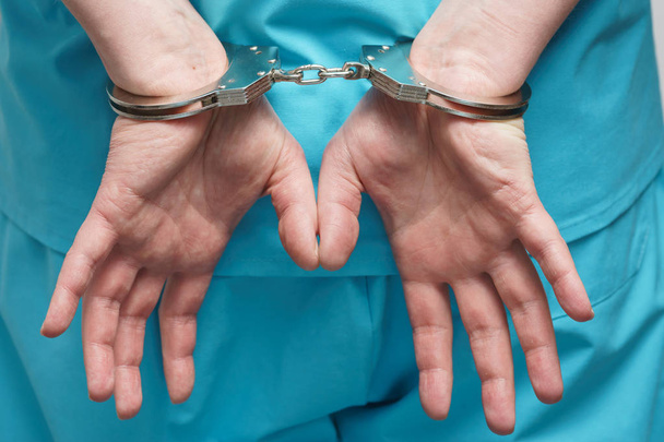 Юнг-доктор в синей форме со стетоскопом, пристегнутым наручниками на запястье.
. - Фото, изображение