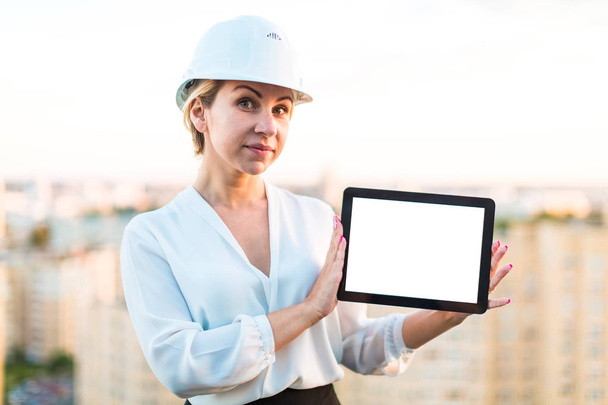 Mujer de negocios en casco en el techo con tableta
 - Foto, Imagen