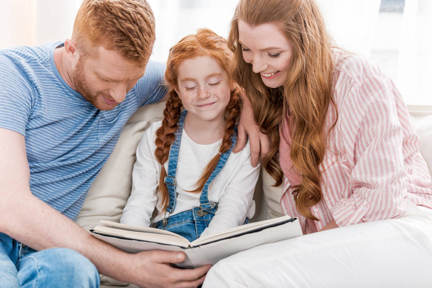 Parents with daughter reading book   - Foto, afbeelding