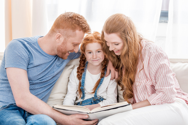 Padres con hija leyendo libro
   - Foto, Imagen