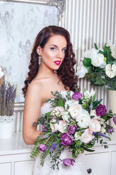 Young attractive bride with flowers indoors . Bride's morning. Happy Bride waiting groom. - Photo, Image