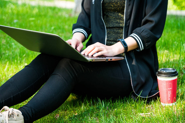 Женщина сидит на траве, используя ноутбук
 - Фото, изображение