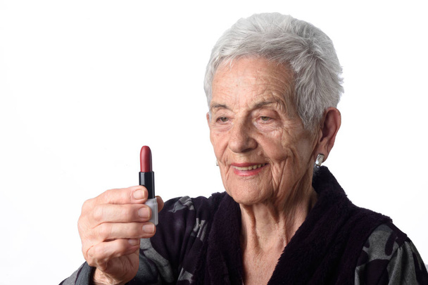 alte Frau bemalt ihre Lippen auf weißem Hintergrund - Foto, Bild