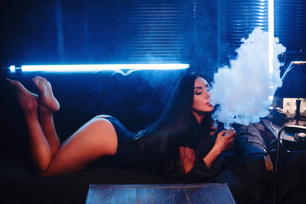 Vaping. Młoda piękna kobieta palenia (vaping) e papieros z intdoors dymu. Koncepcja pary. - Zdjęcie, obraz
