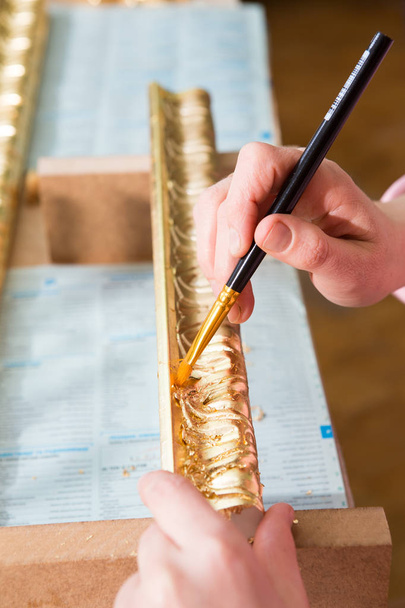 weibliche Handmalerei mit einem Pinsel Baguette für die Decke in Goldfarbe - Foto, Bild