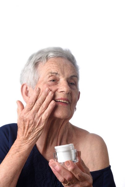 Senior vrouw toepassing huid crème of crème op haar gezicht - Foto, afbeelding