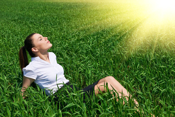 Donna d'affari rilassante nel campo di erba verde all'aperto sotto il sole. Bella ragazza vestita in tuta riposo, paesaggio primaverile, luminosa giornata di sole
 - Foto, immagini