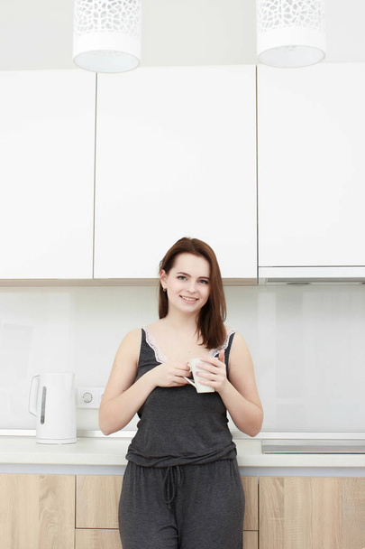 young woman With black hairdrinking coffee in the kitchen - Fotografie, Obrázek