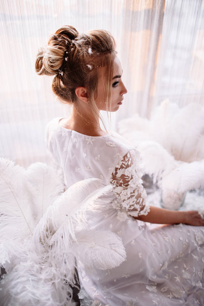 Young beautiful bride in boho style and white feathers. - 写真・画像