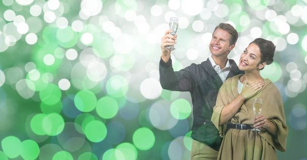 Happy couple holding champagne flutes over bokeh - Фото, изображение