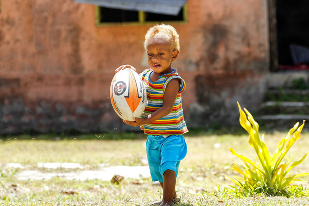 ЛАВЕНА, Фиджи - 27 НОЯБРЯ: Неопознанный мальчик играет с регби ба
 - Фото, изображение
