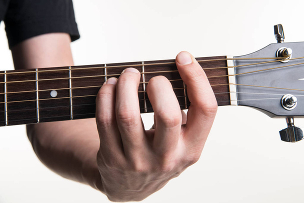 La main du guitariste serre l'accord F sur la guitare, sur fond blanc. Cadre horizontal
 - Photo, image