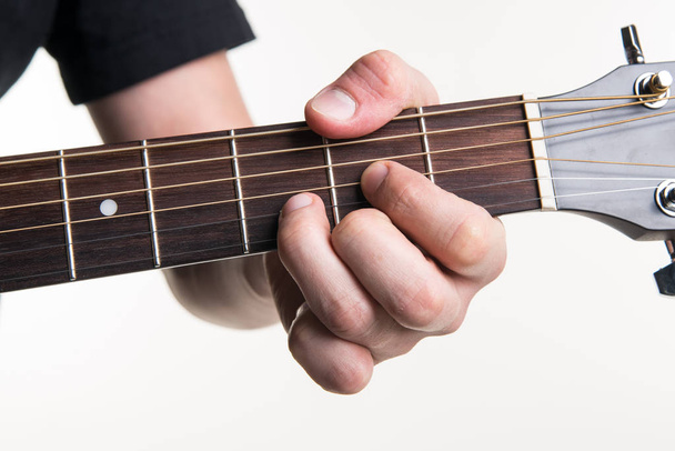 Рука гитариста зажимает аккорд D на гитаре на белом фоне. Горизонтальная рамка
 - Фото, изображение