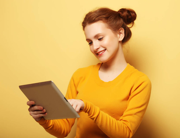 young woman with tablet pc over yellow background - Fotografie, Obrázek